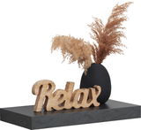Wandboard mit schwarzer Marmoroptik, darauf eine schwarze Vase mit getrocknetem Pampasgras und ein Holzschriftzug 'Relax', seitliche Perspektive