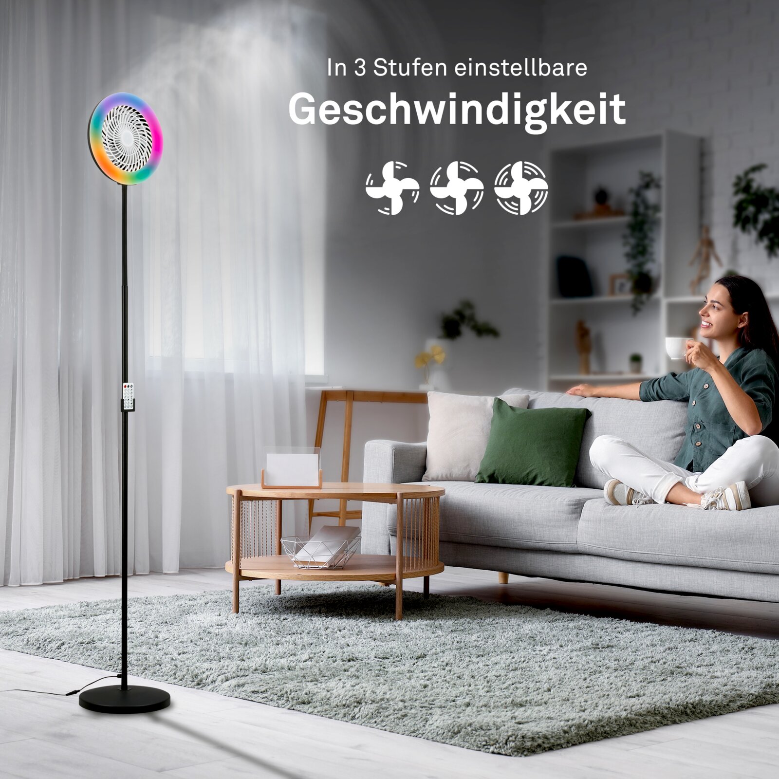 Frontale Produktansicht eines schwarzen Standventilators mit RGB-LED-Ring im Wohnzimmer neben einem Sofa; Text weist auf 3-stufig einstellbare Geschwindigkeit hin.