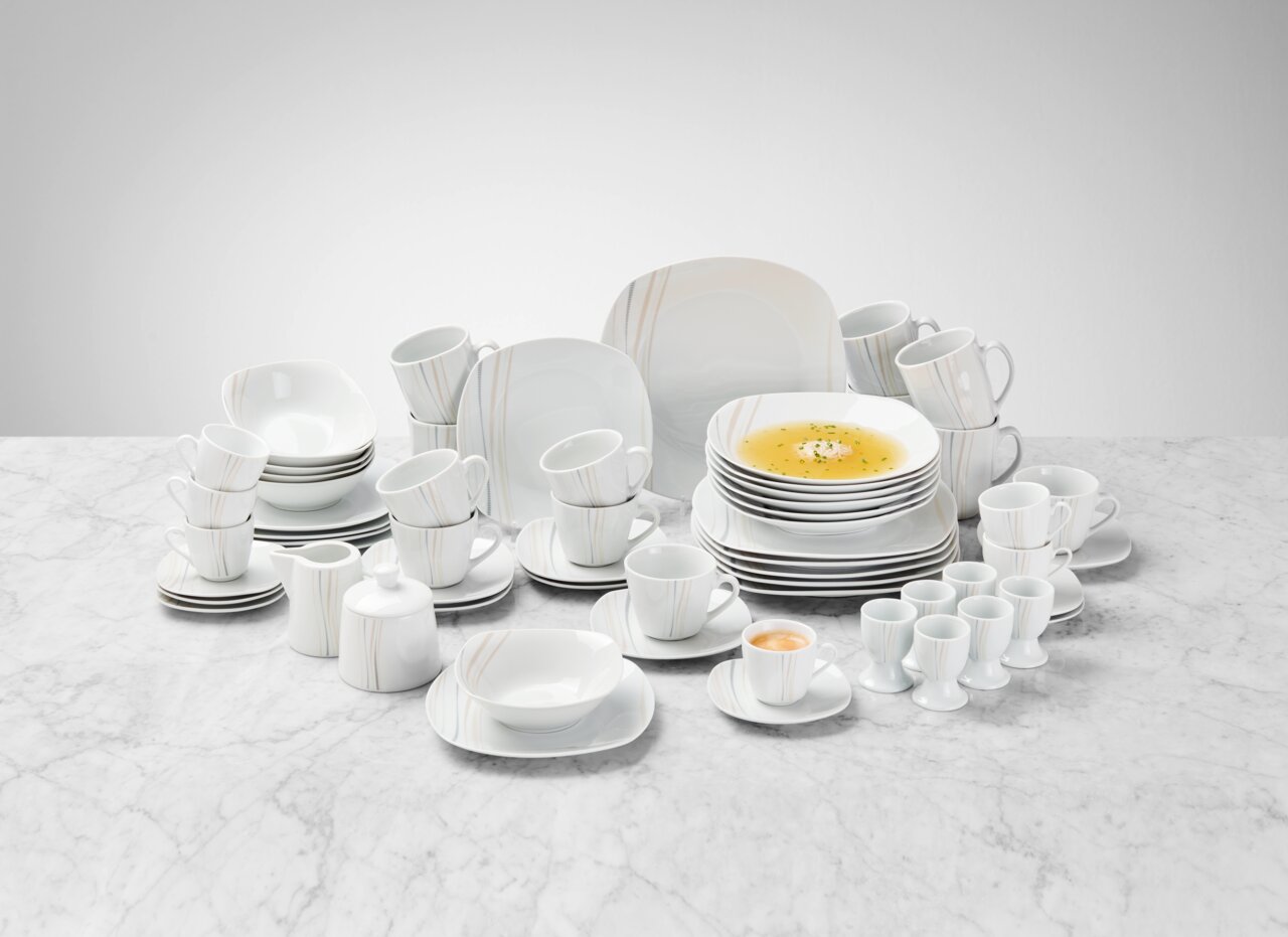 Novel Kombiservice 62-tlg. Kombiservice 62-tlg. aus weißem Porzellan mit dezentem Streifenmuster, bestehend aus Tellern, Tassen, Schalen und Eierbechern, auf einer Marmoroberfläche aus der Vogelperspektive präsentiert.