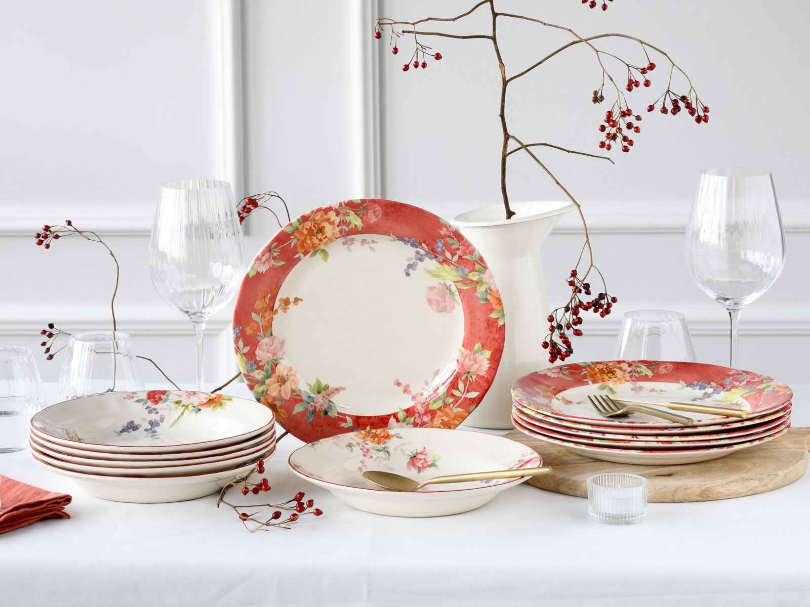 Creatable Tafelservice 12-tlg CRIMSON Blumiges Tafelservice aus Porzellan mit roten Tellerrändern und floralen Motiven, arrangiert mit Gläsern und Vase auf einem Tisch; Perspektive: frontale leicht erhöhte Ansicht.