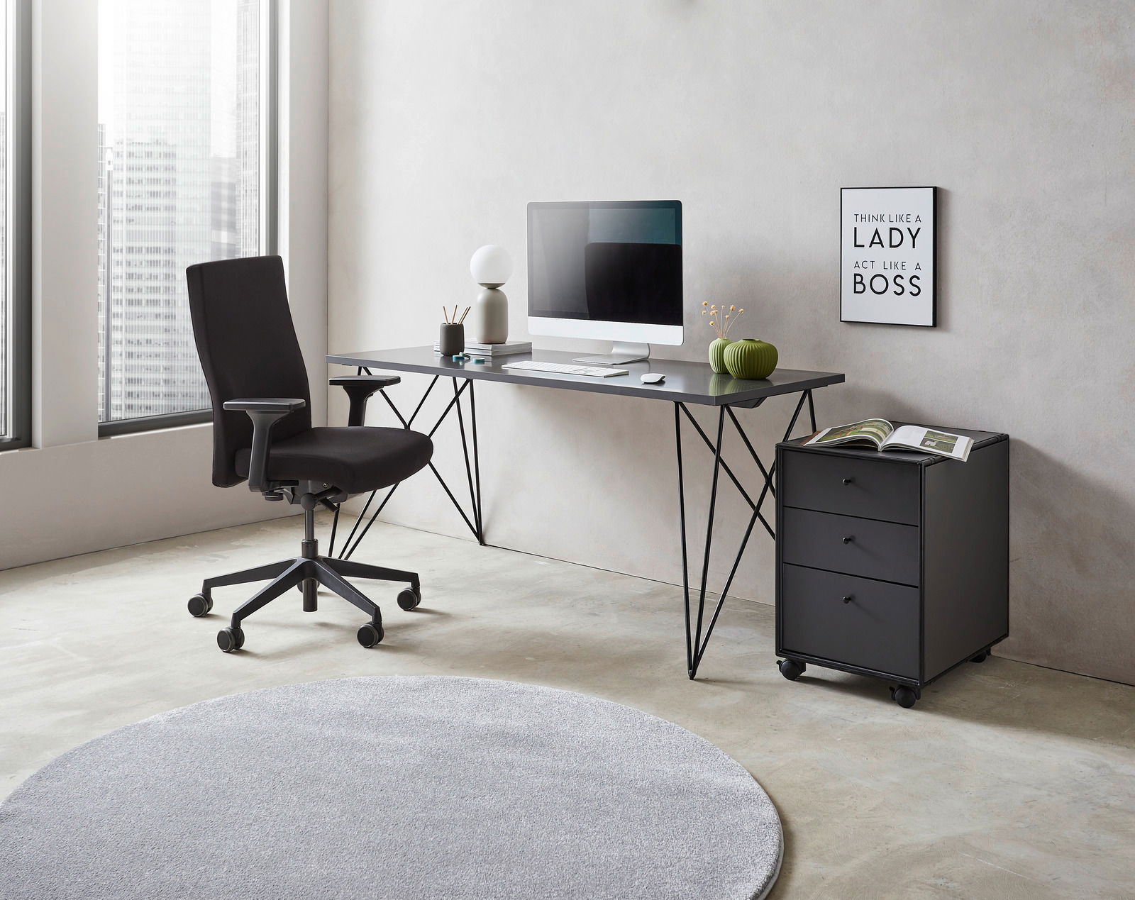 Moderner Schreibtisch mit schwarzem Metallgestell, Computer und Dekorationen, seitliche Perspektive