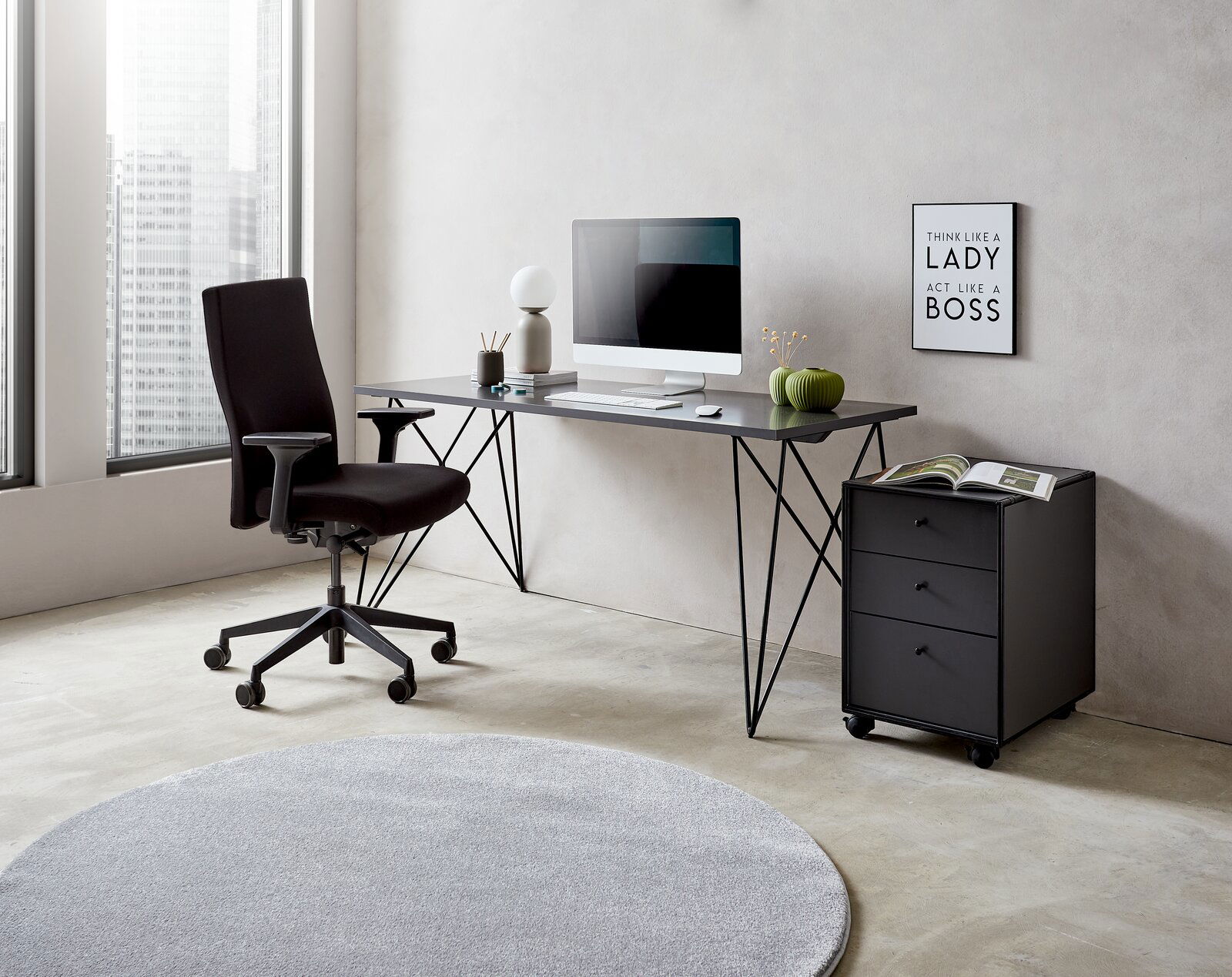 Moderner Schreibtisch mit schwarzem Metallgestell, Computer und Dekorationen, seitliche Perspektive