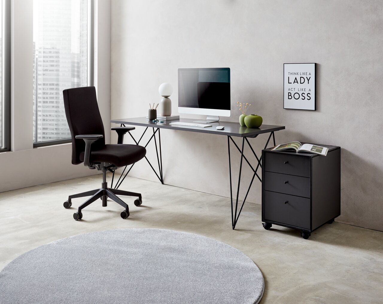 Moderner Schreibtisch mit schwarzem Metallgestell, Computer und Dekorationen, seitliche Perspektive