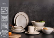 Set aus beigen Steingutgeschirr mit reaktiver Glasur, bestehend aus Tellern, Schalen und Tassen, auf schwarzem Hintergrund, seitliche Perspektive.