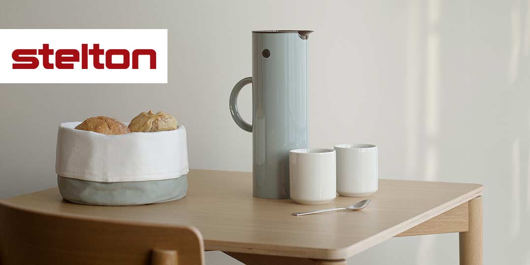 Holztisch mit Thermoskanne, zwei Tassen und Brotkorb der Marke Stelton