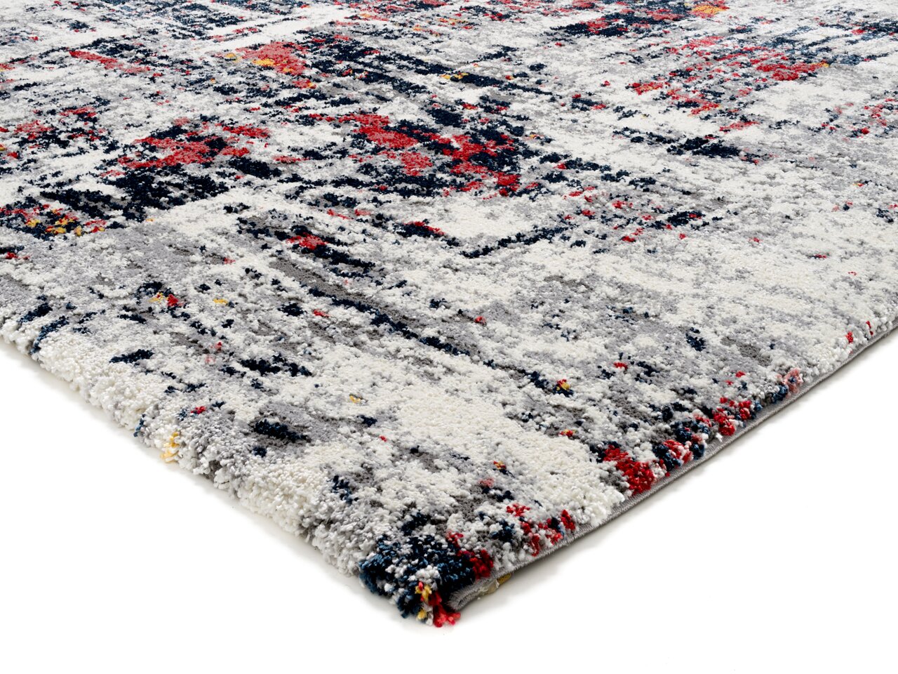 Nahaufnahme eines Designer-Teppichs mit abstraktem Muster in Grau, Rot und Blau, perspektivisch von der Seite aufgenommen.