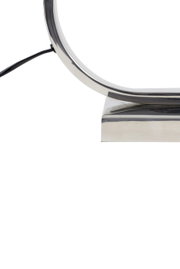 Close-up van een moderne, gebogen metalen lampvoet met kabel, gezien vanaf de zijkant.