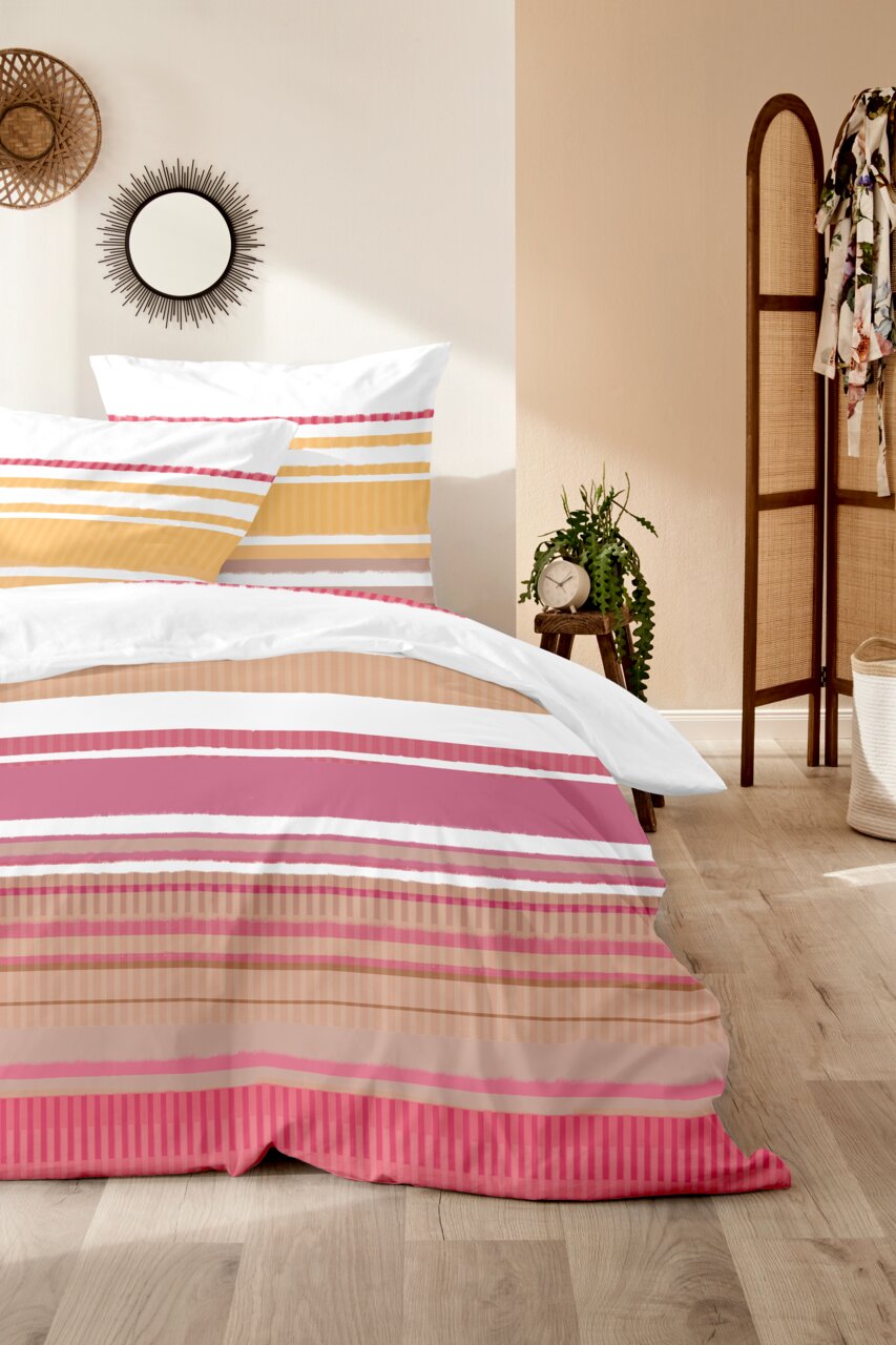 Bettwäsche-Set mit Streifenmuster in Rosa, Gelb und Weiß, auf einem Bett in einem gemütlichen Schlafzimmer, seitliche Perspektive.