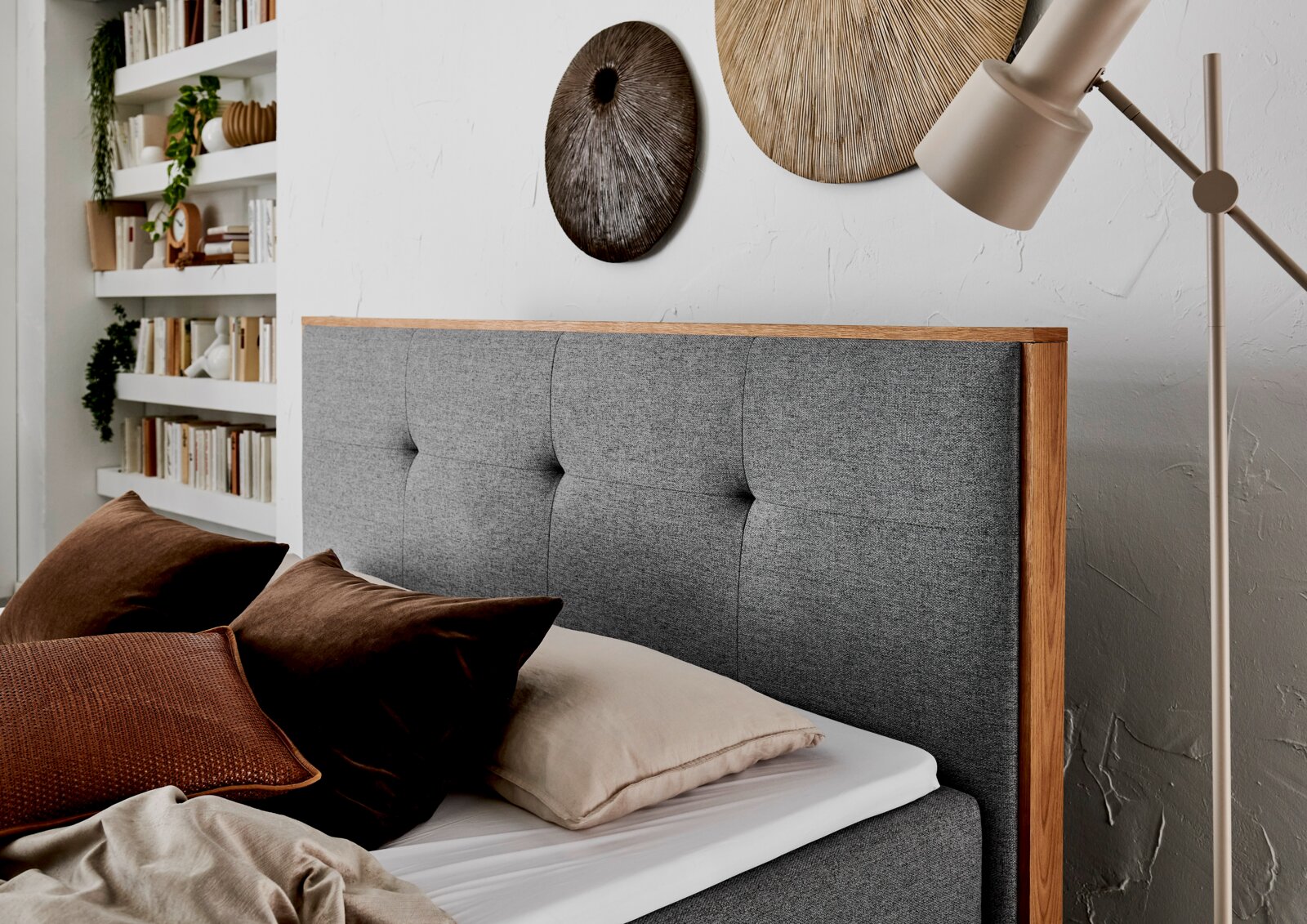 Grijs boxbed met houten frame, versierd met bruine kussens, zijaanzicht