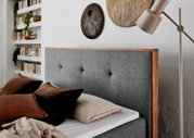 Grijs boxbed met houten frame, versierd met bruine kussens, zijaanzicht