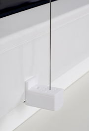 Nahaufnahme eines weißen Plissee-Halters mit gefädeltem Draht, montiert an einem Fensterrahmen.