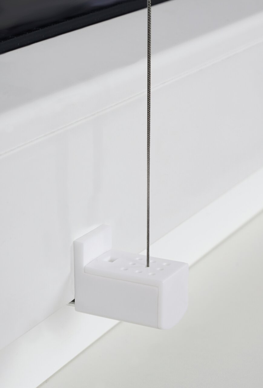 Close-up van een witte plissé-houder met ingeregen draad, bevestigd aan een raamkozijn.