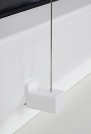 Close-up van een witte plissé-houder met ingeregen draad, bevestigd aan een raamkozijn.