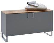 Garderobenbank in modernem Design mit grauer Front und Holzoberfläche, darauf ein Kissen und eine Zeitschrift, Perspektive von vorne.