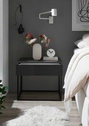 Moderne Nachtkommode in dunklem Design mit dekorativer Vase und Uhr, seitliche Perspektive