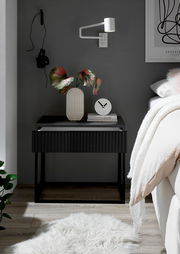 Moderne Nachtkommode in dunklem Design mit dekorativer Vase und Uhr, seitliche Perspektive