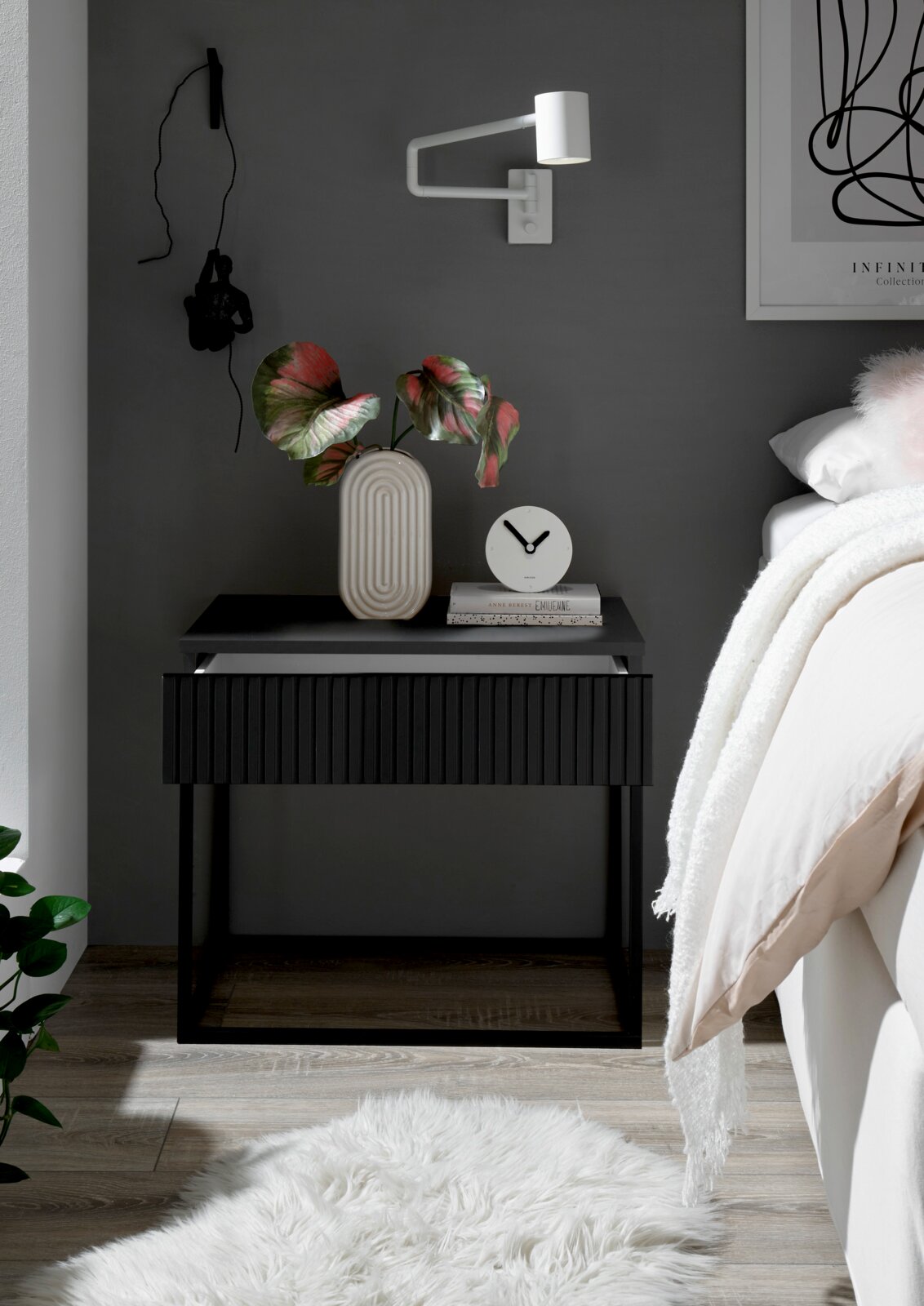 Moderne nachtkastje in donkere uitvoering met decoratieve vaas en klok, zijaanzicht