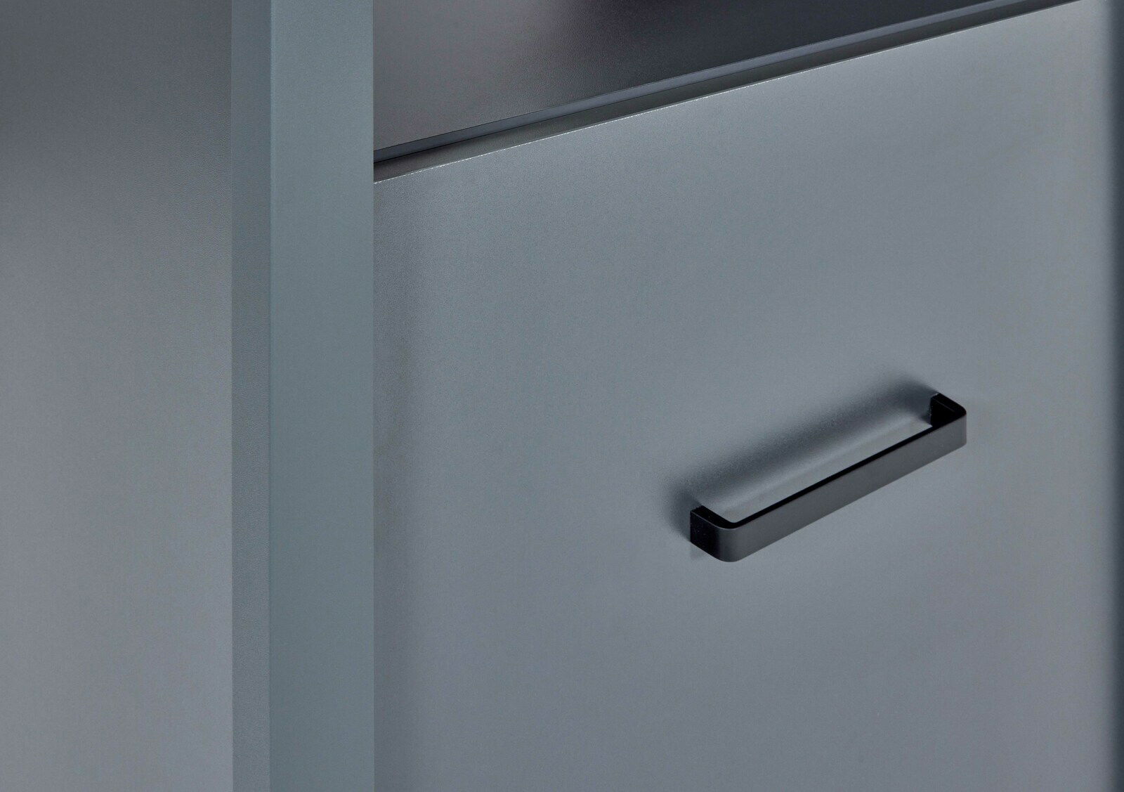 Nahaufnahme eines grauen Herd-Umbauschranks mit schwarzem Griff, seitliche Perspektive