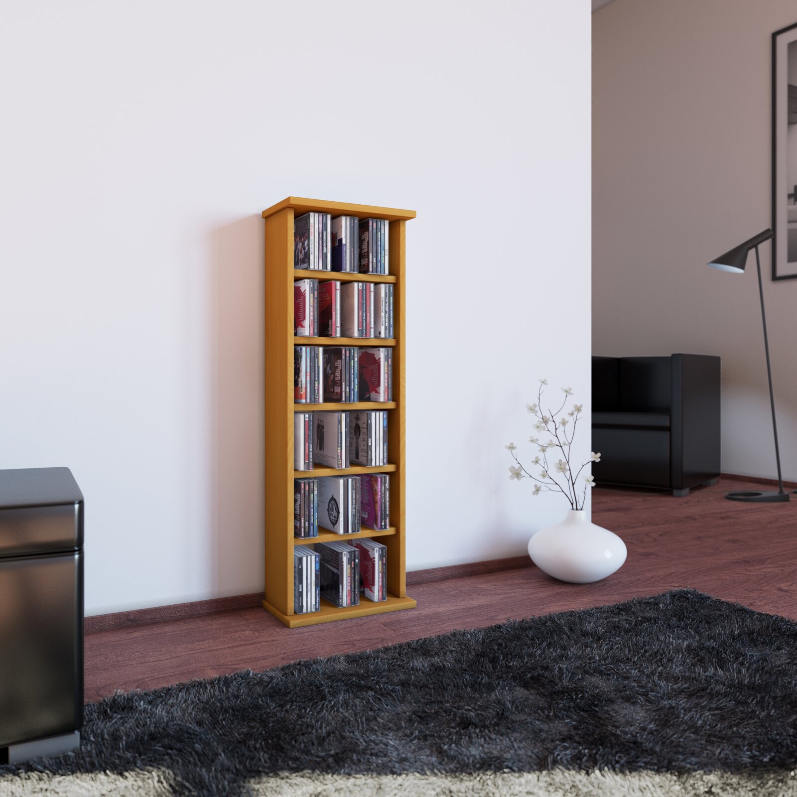 Schmales, hohes CD-Regal aus hellem Holz mit mehreren Fächern, gefüllt mit CDs, freistehend an einer weißen Wand im Wohnzimmer; Perspektive: frontale Ansicht leicht von links auf Augenhöhe.