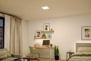 Quadratische LED-Deckenleuchte in Weiß als Aufputzlampe, eingeschaltet in einem modernen Schlafzimmer/Homeoffice – Ansicht schräg von unten (Untersicht) mit Blick auf die Decke.