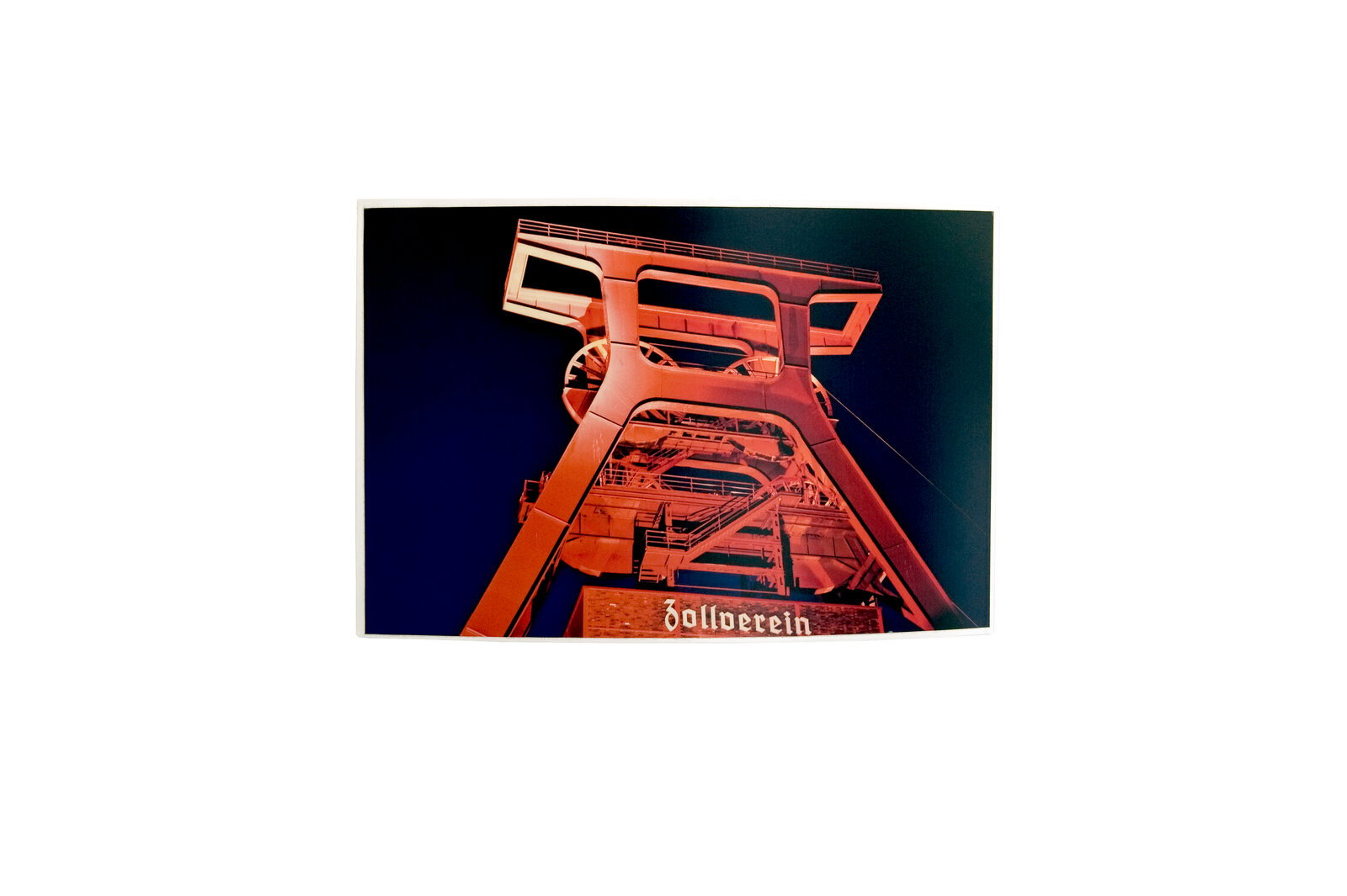 Foto des beleuchteten Förderturms der Zeche Zollverein bei Nacht, von unten aufgenommen.