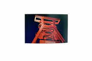 Foto van de verlichte schachttoren van de Zollverein-kolenmijn bij nacht, gefotografeerd vanaf de grond.