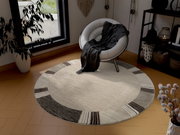 Runder Frisé-Teppich in einem modernen Wohnzimmer, aus der Vogelperspektive fotografiert. Der Teppich hat ein dezentes Muster in Beige- und Brauntönen und liegt auf einem Holzboden neben einem weißen Sessel.