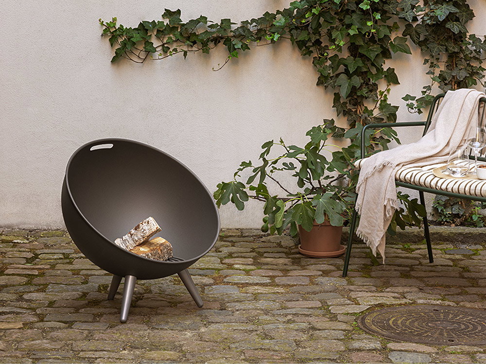 Gemütlicher Innenhof mit Feuerschale, Sitzbank und Pflanzen im urbanen Gartenstil