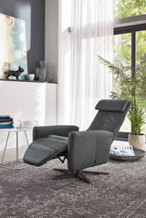 Moderner Relaxsessel in dunklem Leder mit ausgeklapptem Fußteil, seitliche Perspektive in einem hellen Wohnzimmer mit großen Fenstern.