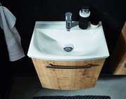 Waschbecken mit Holzunterschrank, von oben fotografiert, mit Handtuch und Accessoires.