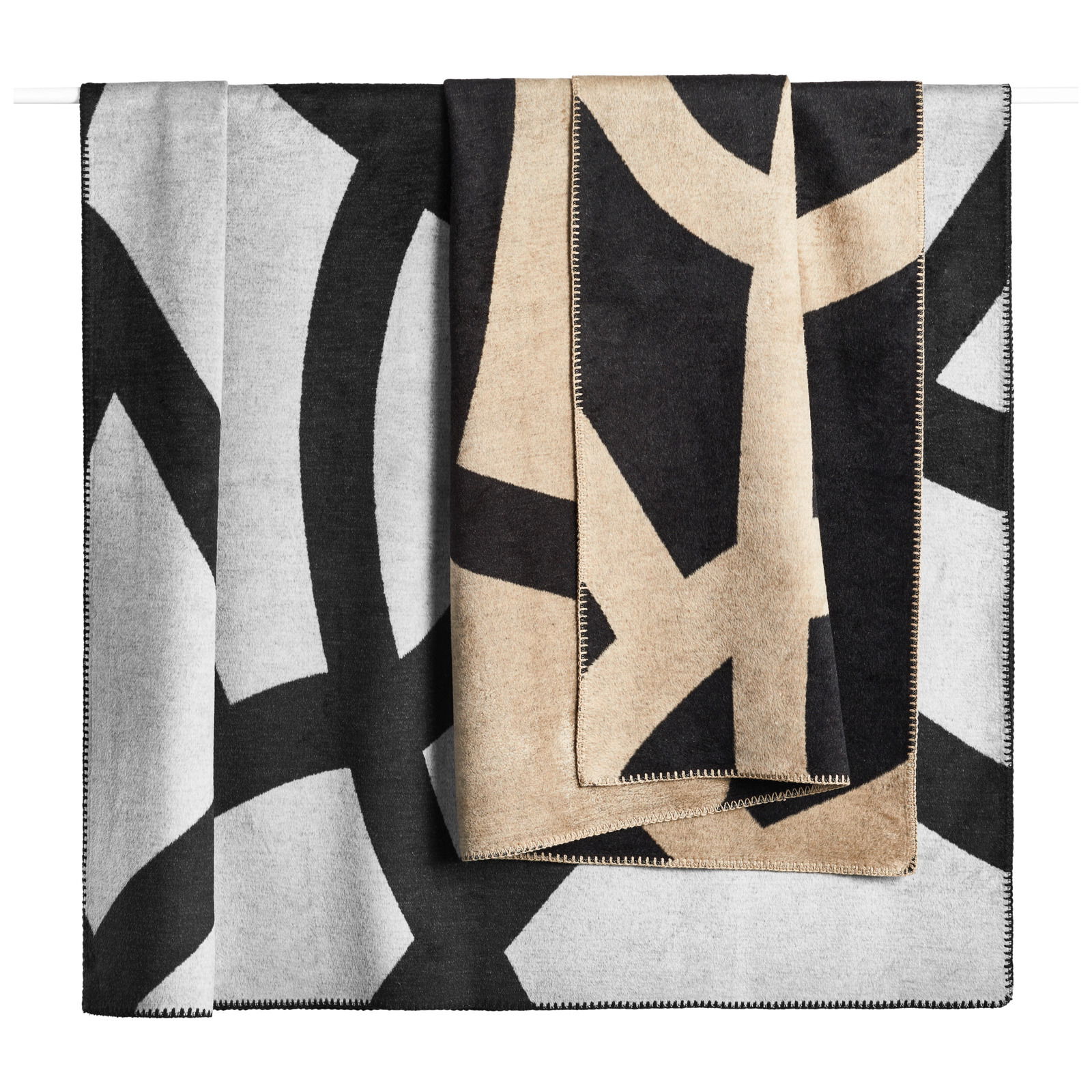 Wohndecke mit abstraktem Muster in Schwarz, Grau und Beige, frontal aufgehängt.