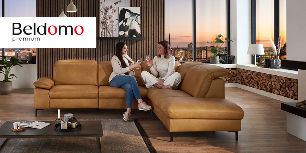 Zwei Frauen sitzen auf einem braunen Ecksofa der Marke Beldomo Premium