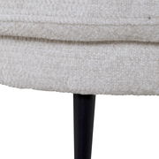 Nahaufnahme eines hellen, texturierten Stoffes mit schwarzem, schlankem Bein. Perspektive von der Seite.