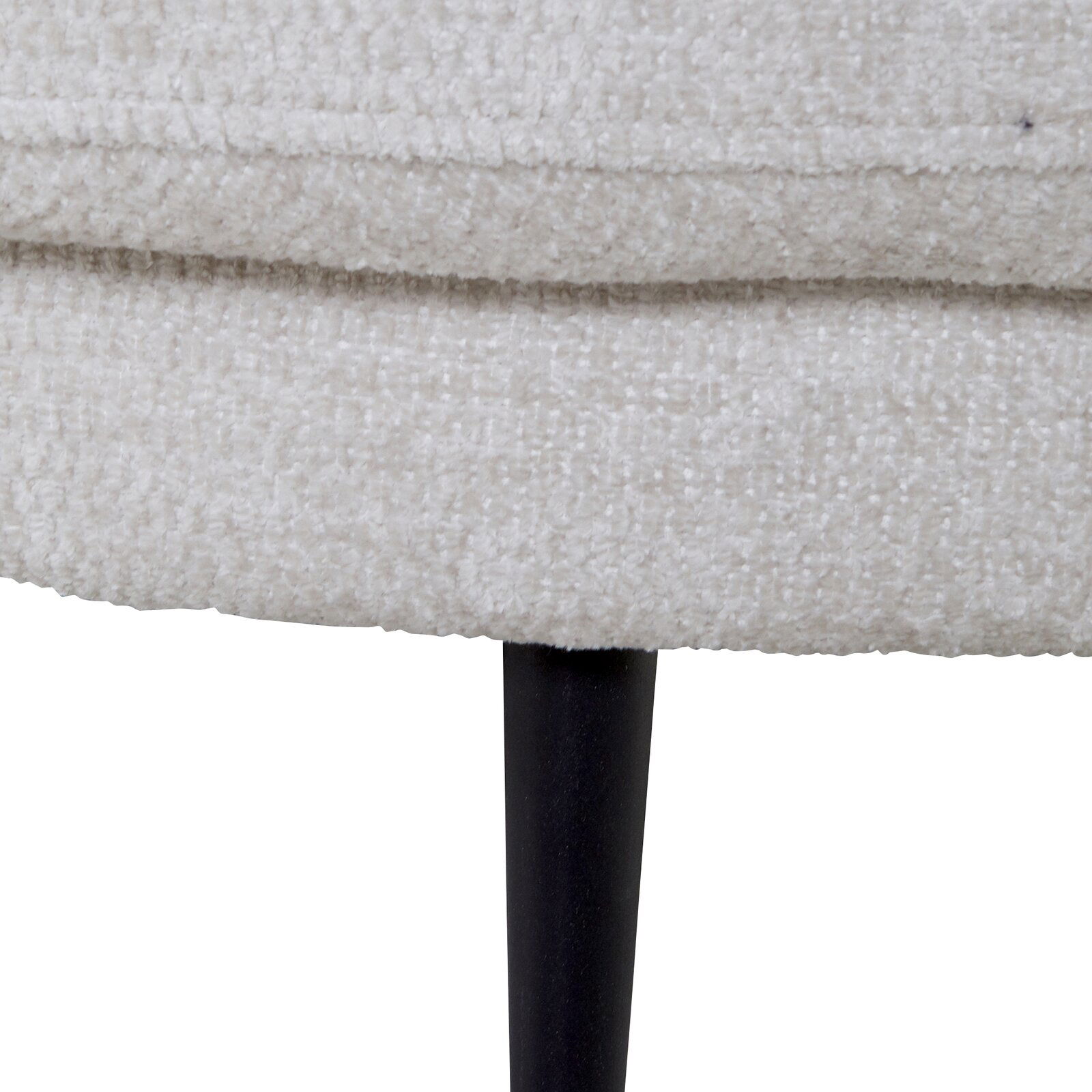 Nahaufnahme eines hellen, texturierten Stoffes mit schwarzem, schlankem Bein. Perspektive von der Seite.