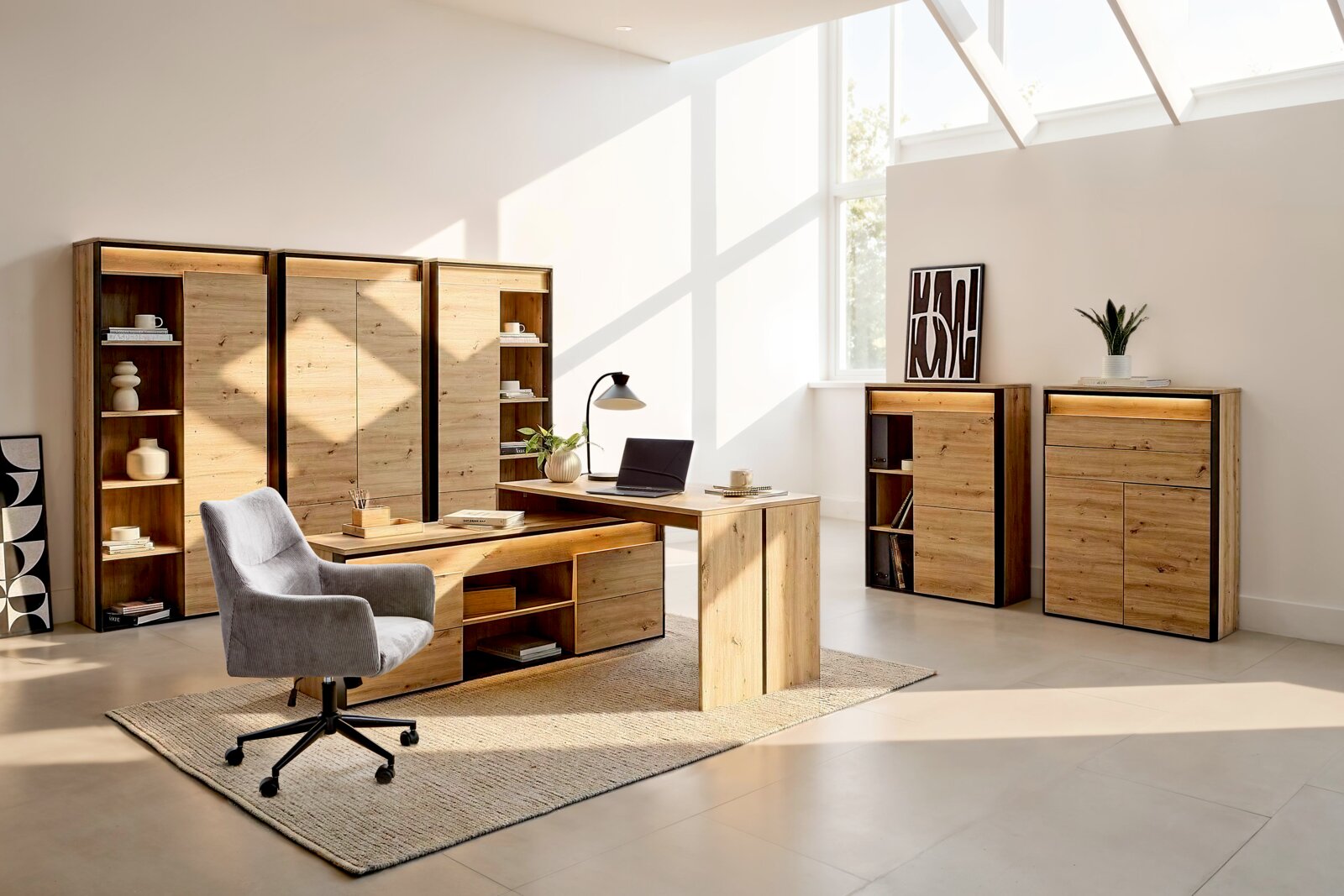 Moderne Büromöbel-Kollektion in natürlicher Holzoptik mit Schreibtisch, Stauraumschränken und Regalen, aus schräger Vorderansicht in einem hellen Homeoffice präsentiert