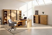 Moderne Büromöbel-Kollektion in natürlicher Holzoptik mit Schreibtisch, Stauraumschränken und Regalen, aus schräger Vorderansicht in einem hellen Homeoffice präsentiert