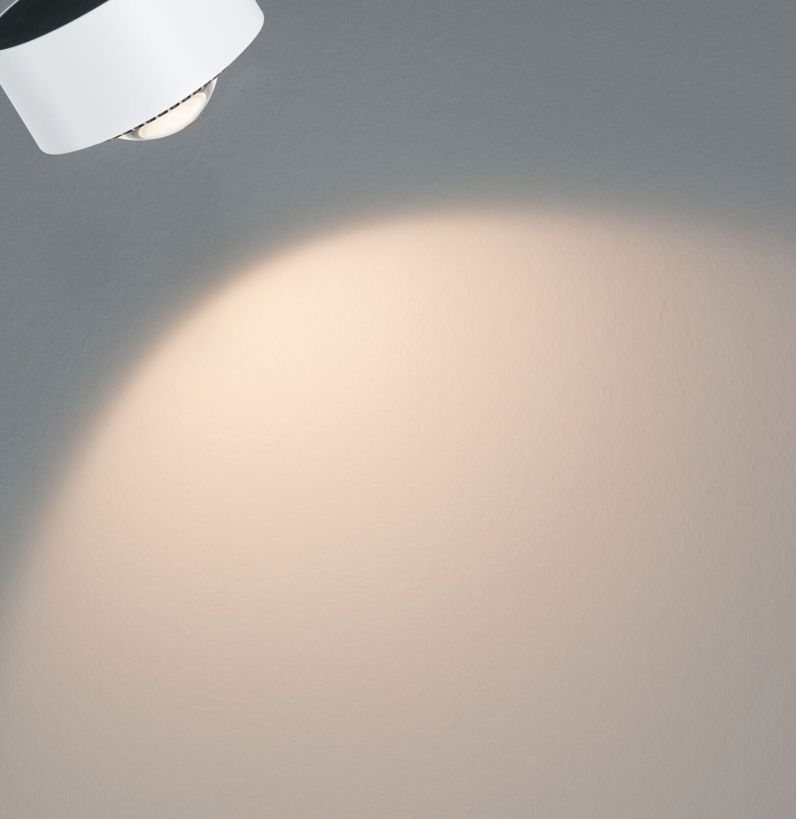 Schienenspot Aldan in weißer Farbe, von der Seite betrachtet, wirft einen warmen Lichtkegel auf eine Wand.