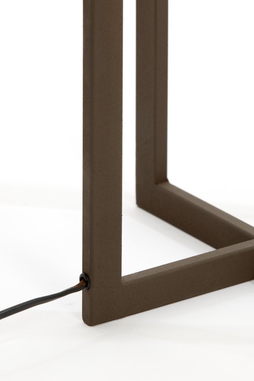 Close-up van het onderste deel van een staande lamp met een bruin metalen frame en een kabel die aan de zijkant naar buiten loopt.