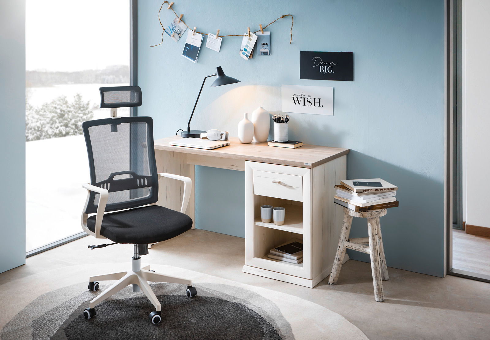Moderner Schreibtisch mit hellem Holzfinish, ausgestattet mit einer Schublade und offenen Regalfächern, daneben ein ergonomischer Bürostuhl mit Netzrückenlehne. Perspektive von vorne.