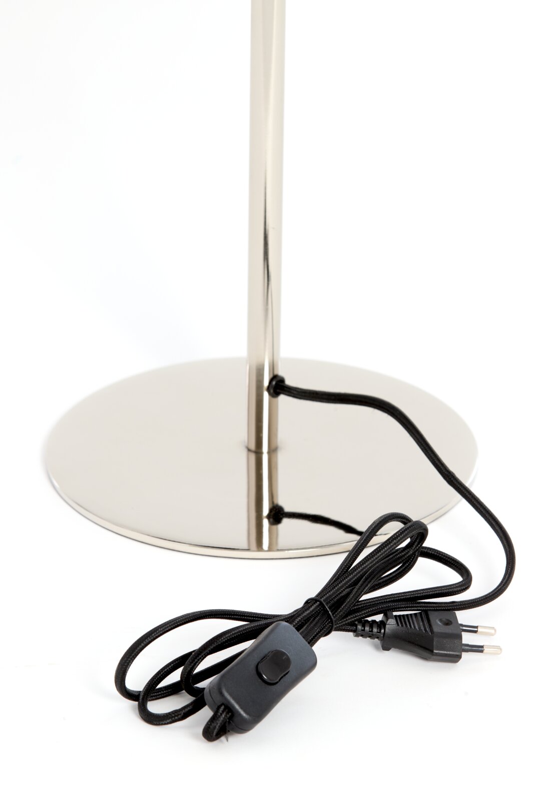 Close-up van de voet van een tafellamp met een glanzende metalen voet en een zwarte kabel met schakelaar.