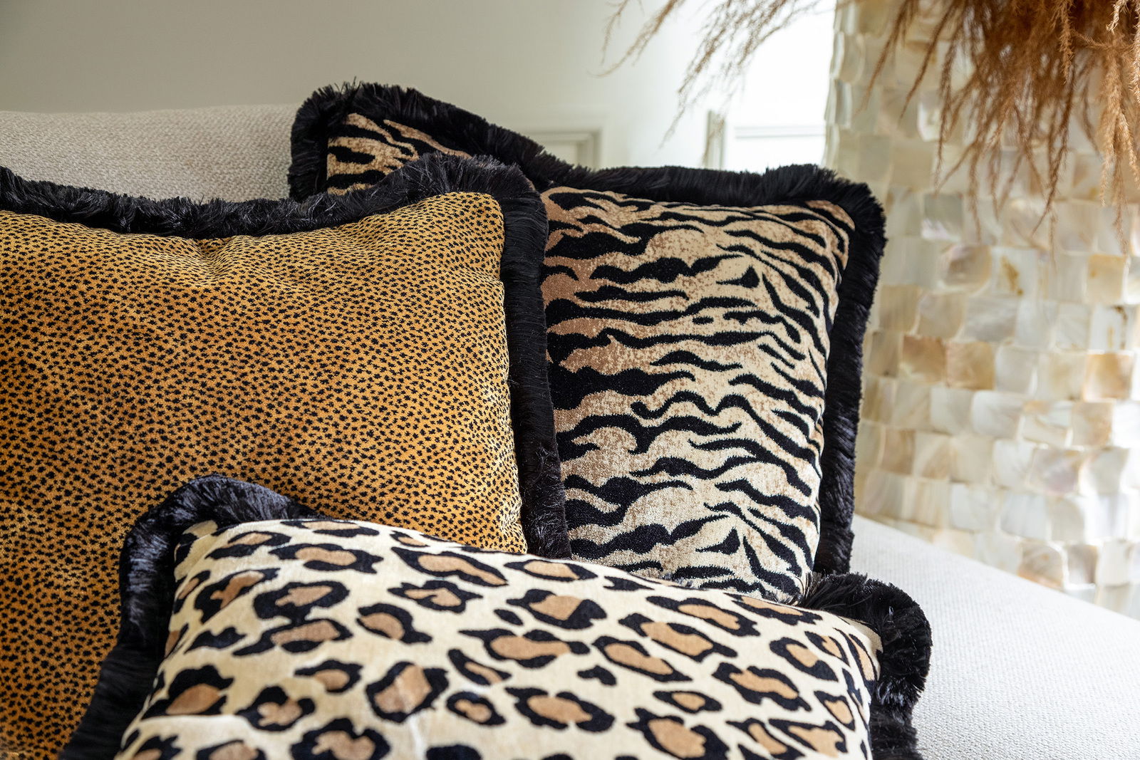 Drei Dekokissen mit Tiermuster in Nahaufnahme auf einem Sofa, Perspektive von vorne.