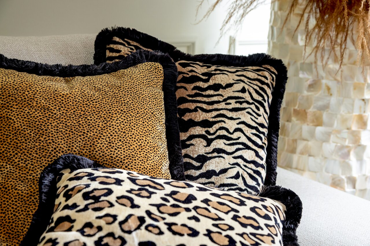 Drei Dekokissen mit Tiermuster in Nahaufnahme auf einem Sofa, Perspektive von vorne.