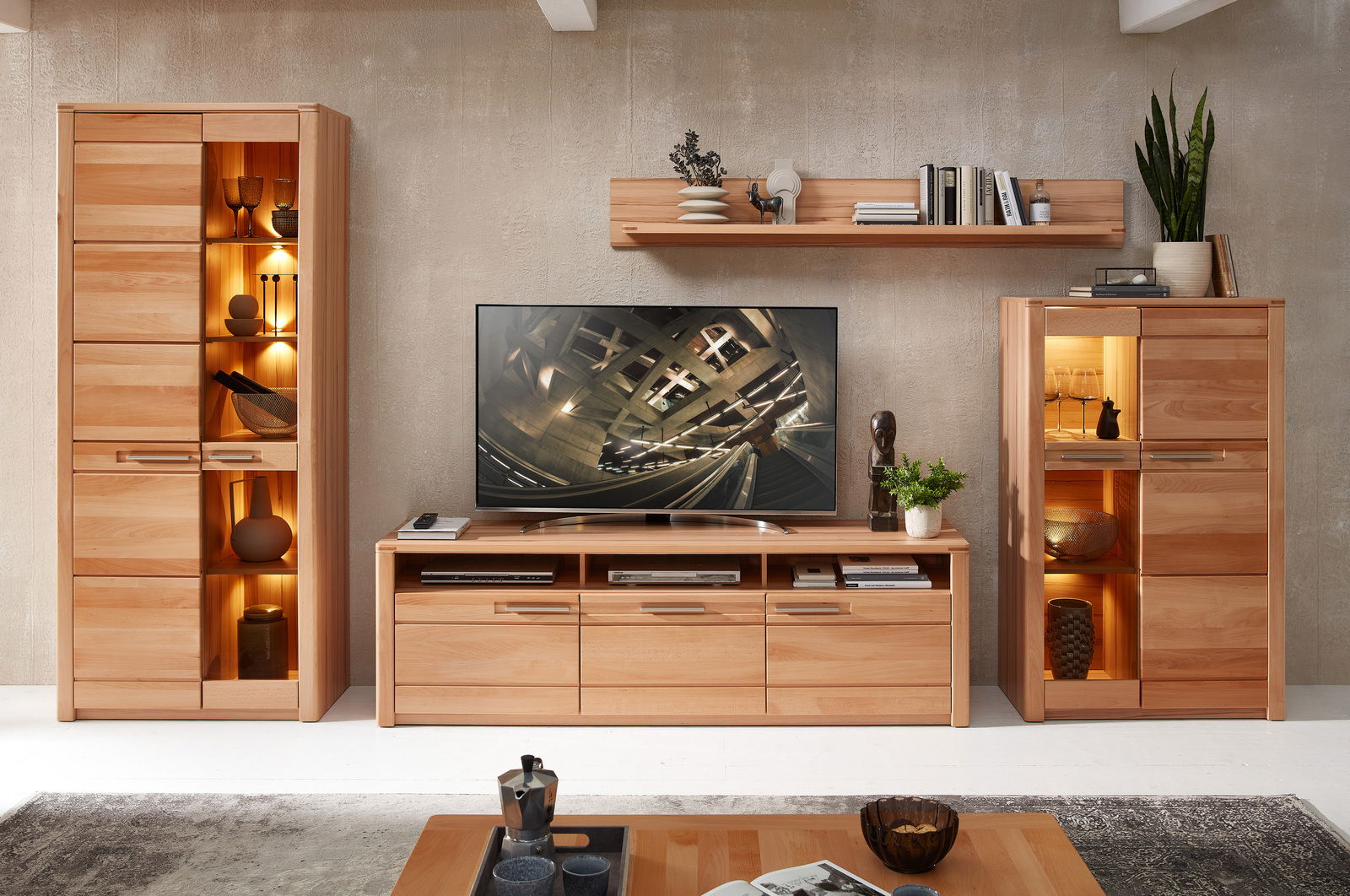 TV-Lowboard aus Holz in einem modernen Wohnzimmer, frontal betrachtet, mit Dekorationen und einem Fernseher darauf.