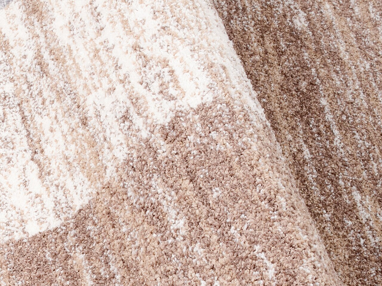 Nahaufnahme eines Frisé-Teppichs in Beige- und Brauntönen mit weicher, strukturierter Oberfläche.