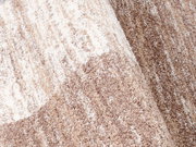 Nahaufnahme eines Frisé-Teppichs in Beige- und Brauntönen mit weicher, strukturierter Oberfläche.