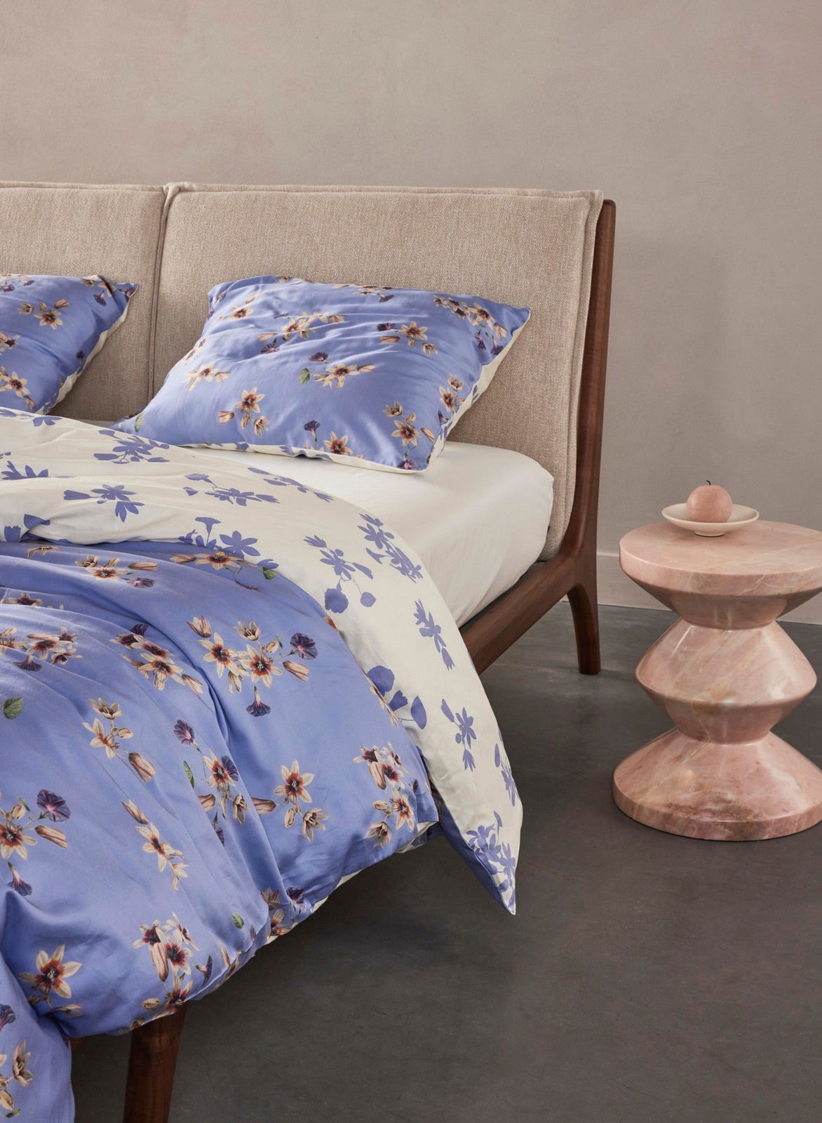 Bett mit blauer und weißer Bettwäsche mit Blumenmuster, seitliche Perspektive