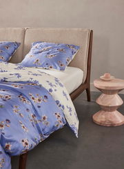 Bett mit blauer und weißer Bettwäsche mit Blumenmuster, seitliche Perspektive