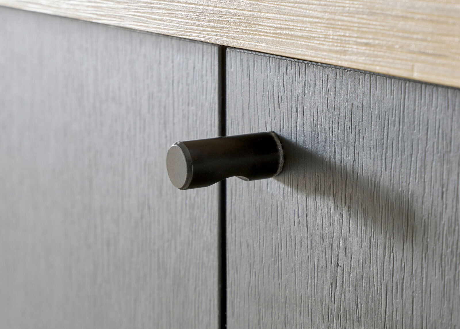 Nahaufnahme eines schwarzen Türgriffs an einem grauen Garderobenschrank, seitliche Perspektive