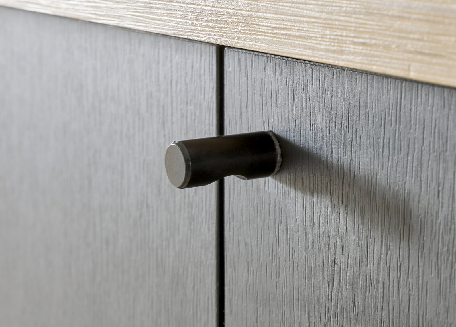Nahaufnahme eines schwarzen Türgriffs an einem grauen Garderobenschrank, seitliche Perspektive