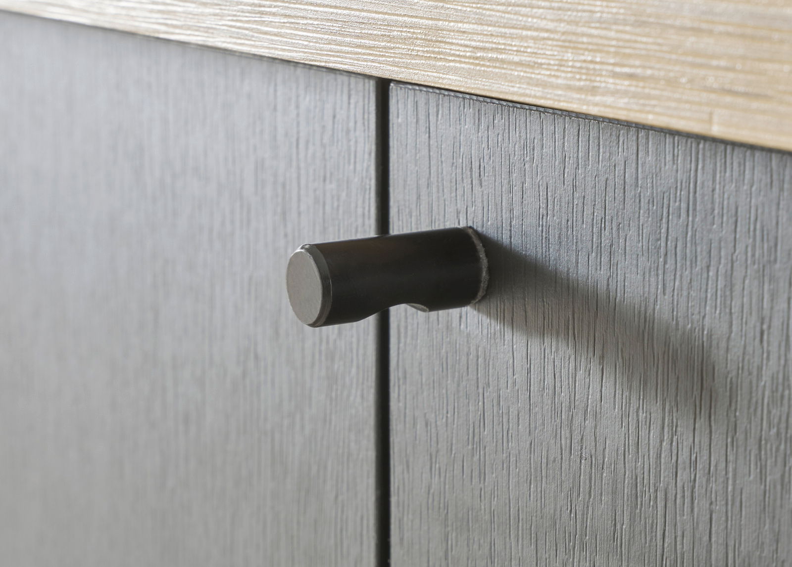 Nahaufnahme eines schwarzen Türgriffs an einem grauen Garderobenschrank, seitliche Perspektive